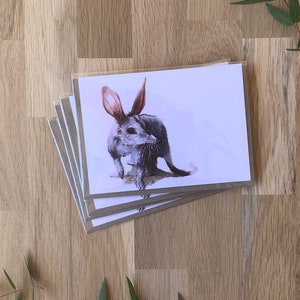 May include: A set of five blank greeting cards featuring a watercolour illustration of a bandicoot. The bandicoot is grey with a long snout and large ears. The cards are stacked on top of each other.
