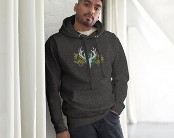 Peut inclure: Sweat à capuche gris foncé avec un motif de bois de cerf blanc, orné de motifs floraux verts et dorés. Le sweat à capuche a une poche avant et une capuche à cordon. La personne porte un sous-vêtement blanc et un jean foncé.