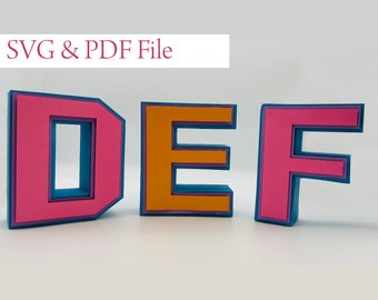 Puede incluir: Tres letras tridimensionales D, E y F, hechas de papel en capas. La D es rosa con una capa interior azul, la E es naranja con una capa interior azul y la F es rosa con una capa interior azul. Las letras están dispuestas en orden, formando la palabra DEF.