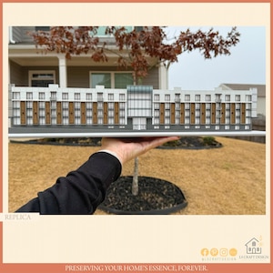 May include: A detailed architectural model of a multi-unit building, held in a person's hand. The model features a white facade with brown accents, windows, and balconies. The word "REPLICA" is visible in the lower left corner.
