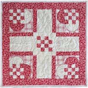 May include: A handmade quilt with a red heart pattern border and accents. The quilt features white blocks with heart-shaped quilting and red and white checkered squares. The design is symmetrical and the edges are finished with a white border.