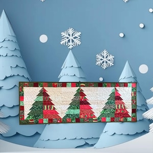 May include: A rectangular quilted table runner featuring three stylized Christmas trees constructed from various red and green patterned fabric squares. The runner has a dark green border and is set against a light blue background with paper trees.