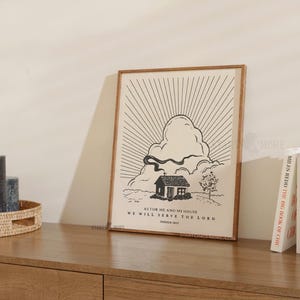 Peut inclure: Une affiche encadr&eacute;e avec une illustration minimaliste en noir et blanc d'une maison, d'un nuage et d'un motif de rayons de soleil. Le texte dit : &laquo; AS FOR ME AND MY HOUSE WE WILL SERVE THE LORD JOSHUA 24:15 &raquo;. Le cadre est de couleur marron clair.