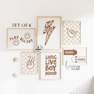 May include: Set of six brown and white framed prints with various designs, including a skateboard, a peace sign, a smiley face, a lightning bolt, and a hand gesture. The prints have text that reads "Play All Day", "Rad Little Dude", "Long Live Boy Hood", and "Henry Evans".