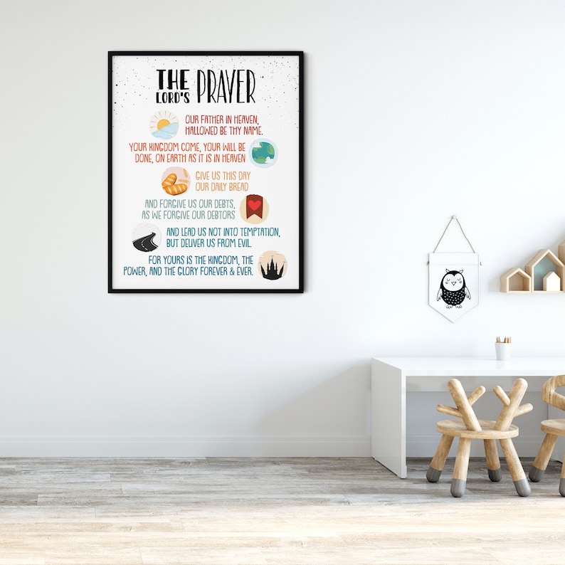 Op de afbeelding: Een ingelijst afdruk van "Het Onze Vader" met kleurrijke illustraties. De tekst is in zwart en wit op een witte achtergrond. De lijst is zwart.