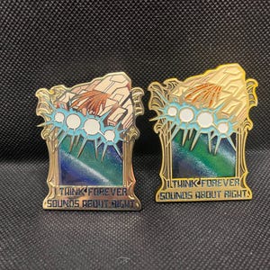 May include: Two gold-colored enamel pins with a rectangular design. Each pin features a stylized landscape with blue, green, and gold accents, and the text "I THINK FOREVER SOUNDS ABOUT RIGHT". The pins have a detailed, ornate border.