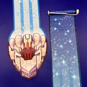 Peut inclure: Une tête de robot blanche et rouge sur un fond bleu et blanc étoilé. La tête du robot a un design détaillé avec un motif en nid d'abeille et des accents rouges.