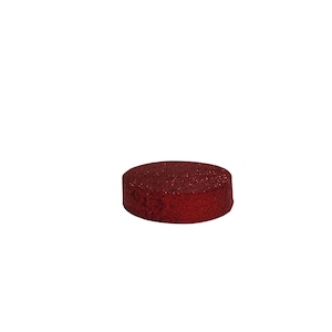 May include: A round, dark red object with a glittery surface. The object is a cylinder shape and appears to be made of a solid material. The background is plain white.