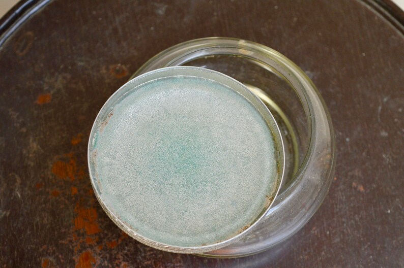 K&ouml;nnte beinhalten: Ein klares Glasgef&auml;&szlig; mit einem mattierten Deckel. Der Deckel hat einen hellblauen Farbton.
