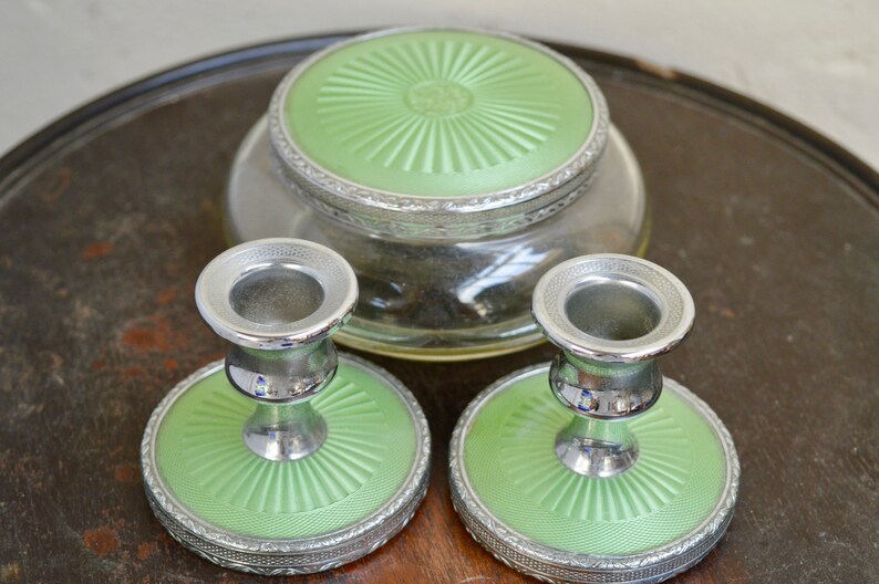 K&ouml;nnte beinhalten: Ein Set aus drei Vintage-Schminkutensilien in Gr&uuml;n und Silber. Das Set enth&auml;lt ein rundes Glas mit Deckel und zwei Kerzenhalter mit passenden Sockeln.
