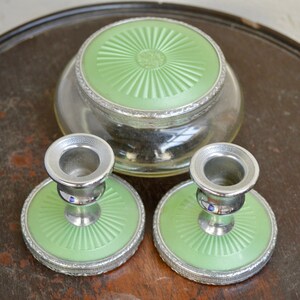K&ouml;nnte beinhalten: Ein Set aus drei Vintage-Schminkutensilien in Gr&uuml;n und Silber. Das Set enth&auml;lt ein rundes Glasgef&auml;&szlig; mit einem gr&uuml;nen Deckel und zwei passende Kerzenhalter mit gr&uuml;nen Sockeln.