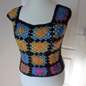 Peut inclure: Un haut en crochet noir avec un motif carré dans des tons de bleu, vert, orange et rose.