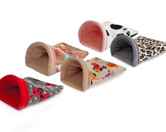 May include: Six colorful fleece hamster sleeping bags. The bags are in various patterns, including ladybugs, flowers, and cow print. The bags are all open at one end, creating a cozy sleeping space for a small pet.