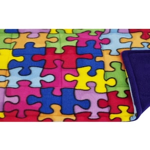 May include: A colourful puzzle piece patterned weighted blanket with a soft purple fleece lining. The blanket is designed to provide sensory input and comfort.