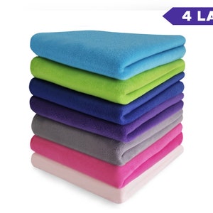 Peut inclure: Une pile de six couvertures en polaire de différentes couleurs, dont bleu clair, vert, bleu, violet, gris et rose. Le texte "4 LAYERS" est visible dans le coin supérieur droit de l'image.