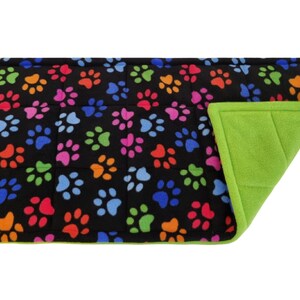 May include: A black pet bed with a colourful paw print pattern on one side and a solid green fleece on the other side.