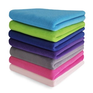 May include: A vertical stack of seven folded fleece blankets in a variety of solid colours, including bright blue, lime green, navy blue, deep purple, charcoal grey, hot pink, and light pastel pink, arranged neatly in a single column.