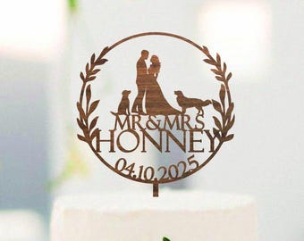 Può includere: Torta nuziale bianca a tre piani con composizione floreale e cake topper in legno. Il topper presenta la silhouette di una coppia, due cani e la scritta "MR & MRS HONNEY 04.10.2025".