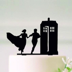 May include: Black silhouette of a couple dancing in front of a blue police box, a popular symbol from the British science fiction television series Doctor Who. This is a cake topper.