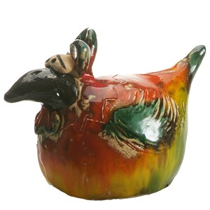 May include: A ceramic chicken figurine featuring a glossy, multi-coloured glaze in shades of red, yellow, and green. The sculpture has a prominent black beak, large eyes, and a textured wing detail, with a rounded body and a pointed tail.