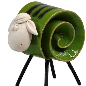 May include: A ceramic sheep figurine featuring a glossy green coiled body with dark brown stripes. The head is matte white with simple facial features, and the figure stands on four thin, straight black legs that support the coiled ceramic structure.