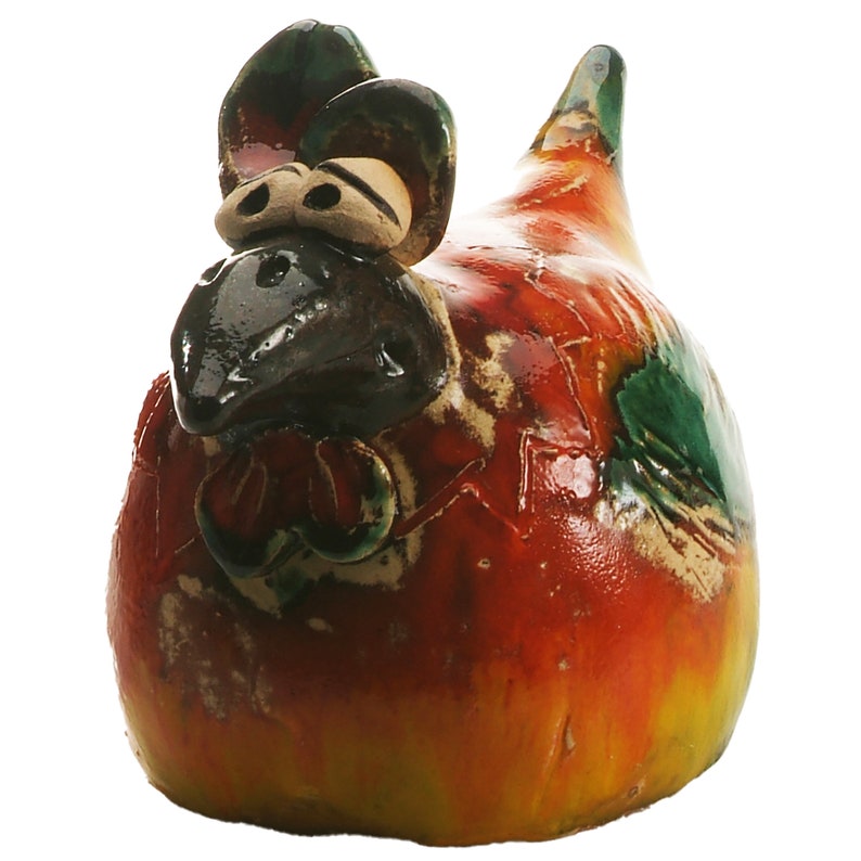 May include: A ceramic chicken figurine featuring a glossy, multi-coloured glaze in shades of vibrant red, yellow, and green. The sculpture has a dark brown beak, prominent eyes, and a textured surface with visible cracks in the glaze finish.