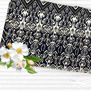 May include: Black and white ikat fabric with a geometric pattern. The fabric is folded and has a white background with black and white geometric designs.
