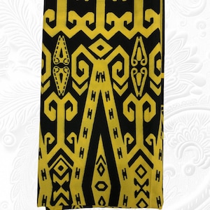 May include: Folded textile with a repeating geometric pattern in black and yellow. The design features stylized shapes, including triangles, diamonds, and curved lines. The fabric is folded neatly, showcasing the intricate pattern. The overall aesthetic is bold and graphic.