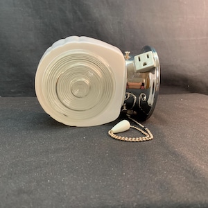 May include: A vintage wall light fitting with a white, frosted glass shade and a clear, concentric-circle design. The fitting has a chrome-finished base with an electrical outlet and a pull chain with a white teardrop-shaped pull.