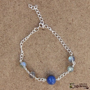 K&ouml;nnte beinhalten: Ein silbernes Kettenarmband mit drei hellblauen und grauen Perlen und einer dunkelblauen Perle.