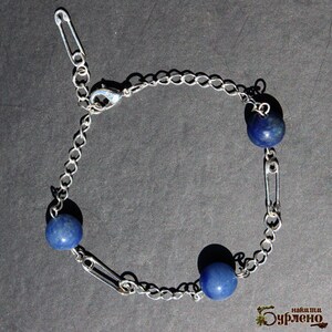 May include: Silver-toned chain bracelet featuring three blue spherical beads. The bracelet design incorporates safety pins as decorative elements, adding a unique touch to the jewelry. The bracelet has a lobster clasp closure.