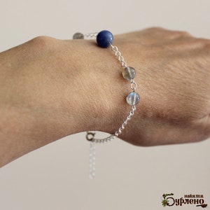 K&ouml;nnte beinhalten: Ein silbernes Kettenarmband mit blauen und schillernden Edelsteinperlen.