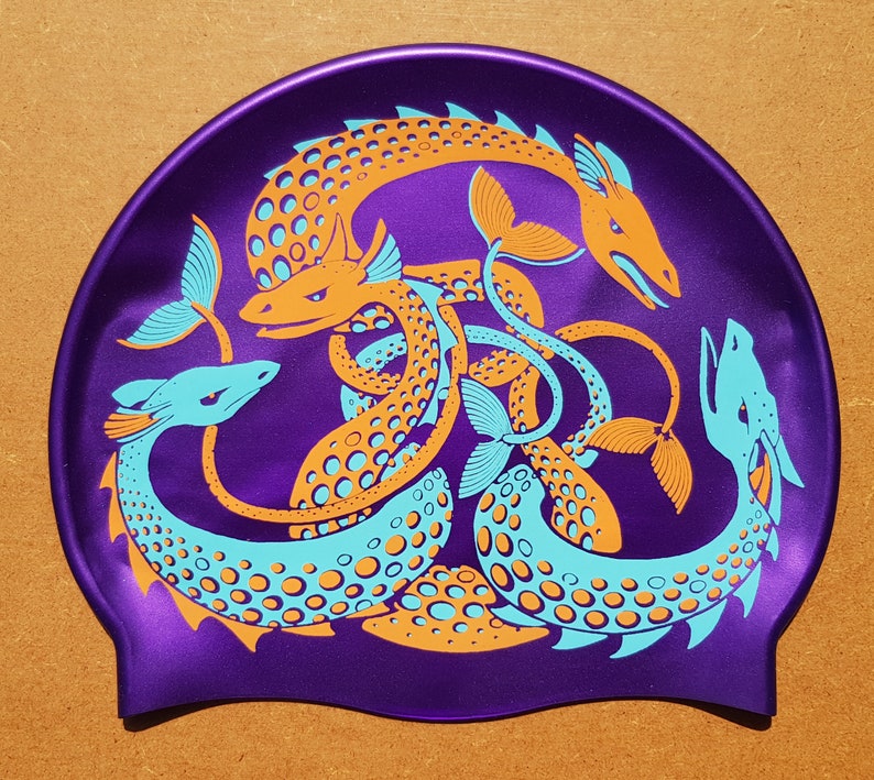 May include: Purple swim cap featuring a stylized design of intertwined sea serpents in orange and teal. The serpents have detailed scales and fins, creating a dynamic and eye-catching pattern. The cap is made of a smooth, shiny material.