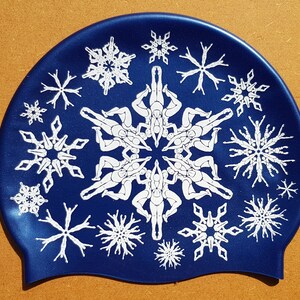May include: A blue and white swimming cap featuring a snowflake design. The snowflakes are formed from stylised figures of people.