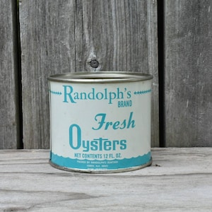 May include: A vintage can of Randolph's Brand Fresh Oysters. The can is white with blue lettering and a blue wave design at the bottom. The can says "Randolph's Brand Fresh Oysters" and "Net Contents 12 Fl. Oz."