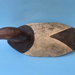 K&ouml;nnte beinhalten: Ein Vintage-Holzentenk&ouml;der, bemalt in Braun-, Schwarz- und Cremet&ouml;nen. Der Entenkopf ist dunkelbraun, mit einem schwarzen und cremefarbenen K&ouml;rper. Der K&ouml;der ist so konzipiert, dass er auf dem Wasser schwimmt und andere Enten anlockt. Ein klassisches St&uuml;ck Volkskunst.