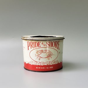 May include: White metal can with red and black lettering that reads "Pride of the Shore Crab Meat" with a red crab illustration. The can has a net weight of 16 ounces (1 lb.) avoirdupois.