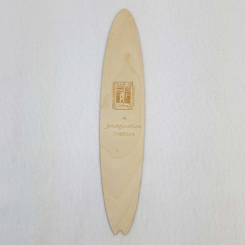 May include: A wooden surfboard bookmark with the text "A Imagination Creation" and "Made in Cornwall" printed on it.