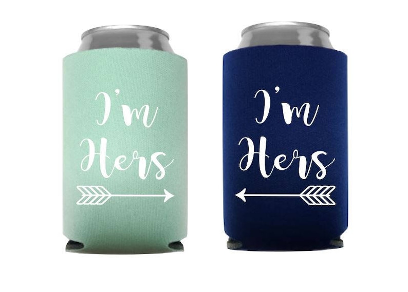May include: Two can coolers, one mint green and one navy blue, with the text "I'm Hers" in white script. Each cooler has a white arrow pointing towards the other. The coolers are designed to keep beverages cold.