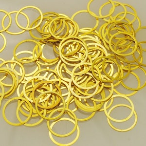 May include: A large pile of gold-colored metal jump rings. The rings are all the same size and are arranged in a random pattern.