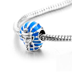 May include: A silver charm bracelet with a blue and silver charm featuring a pharaoh's head.
