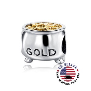 May include: A silver charm in the shape of a pot with a gold top. The pot is filled with gold coins and the word "GOLD" is printed on the side.