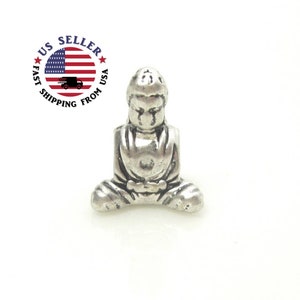 Puede incluir: Pequeña figura de Buda plateada en posición de meditación sentado. La figura tiene una expresión serena y está detallada con pliegues en las túnicas. La imagen incluye un gráfico circular con la bandera de EE. UU. y el texto "US Seller, Fast Shipping From USA."