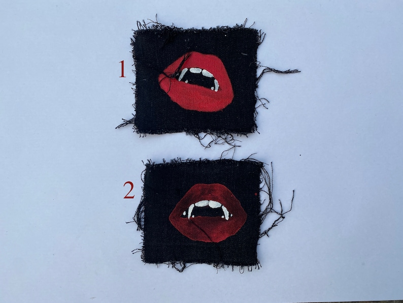 May include: Two black fabric patches with red lips and white fangs. The patches are frayed around the edges. The patches are numbered 1 and 2.