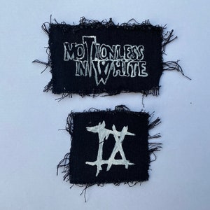 May include: Two black fabric patches with white lettering. The top patch says "Motionless In White". The bottom patch has a white "IX" symbol.