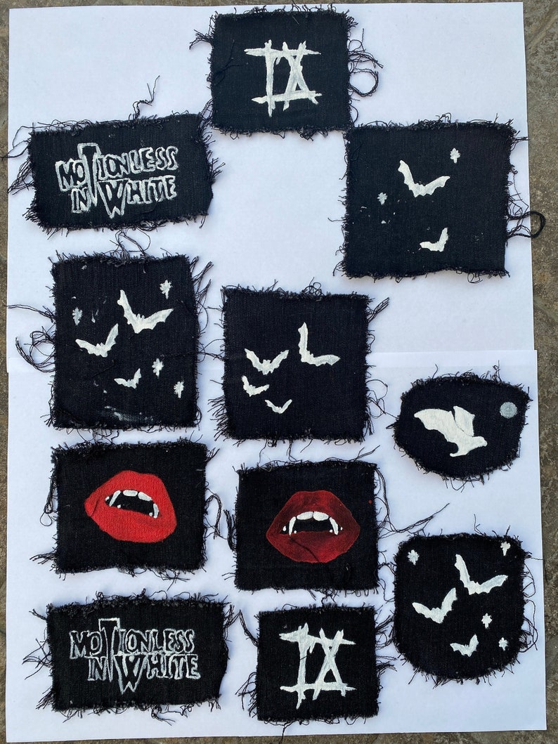 May include: A collection of 10 black fabric patches with white designs. The patches feature various designs, including bats, lips, and the words "Motionless In White" and "IX".