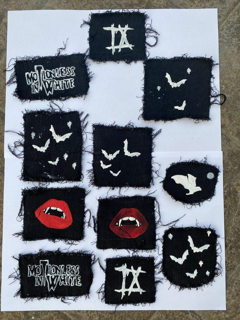 May include: Nine black fabric patches with white embroidered designs. The patches feature the words "Motionless in White", a Roman numeral "IX", and bats. Two patches feature a red, open mouth with fangs.