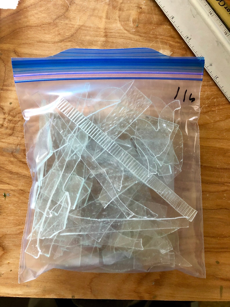 Puede incluir: Una bolsa de pl&aacute;stico transparente con cierre de cremallera azul llena de fragmentos de vidrio transparente de forma irregular. Una regla y el n&uacute;mero "116" son visibles en la bolsa. El contenido parece ser material de manualidades o para proyectos.