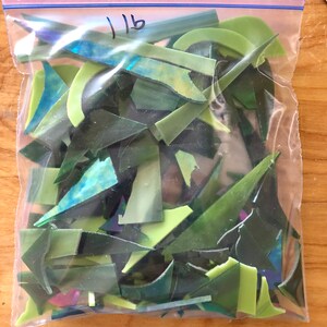Puede incluir: Una bolsa de pl&aacute;stico transparente llena de trozos de vidrio verde de varios tonos. Los trozos de vidrio tienen formas irregulares, incluyendo tri&aacute;ngulos y piezas curvas. La bolsa est&aacute; etiquetada con el n&uacute;mero "1 lb" en rotulador negro.