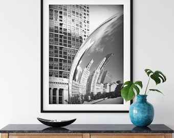 May include: A black and white framed wall art print depicting a distorted reflection of city skyscrapers on a curved metallic surface. The artwork is displayed in a thin black frame, showcasing architectural details and high-contrast light.